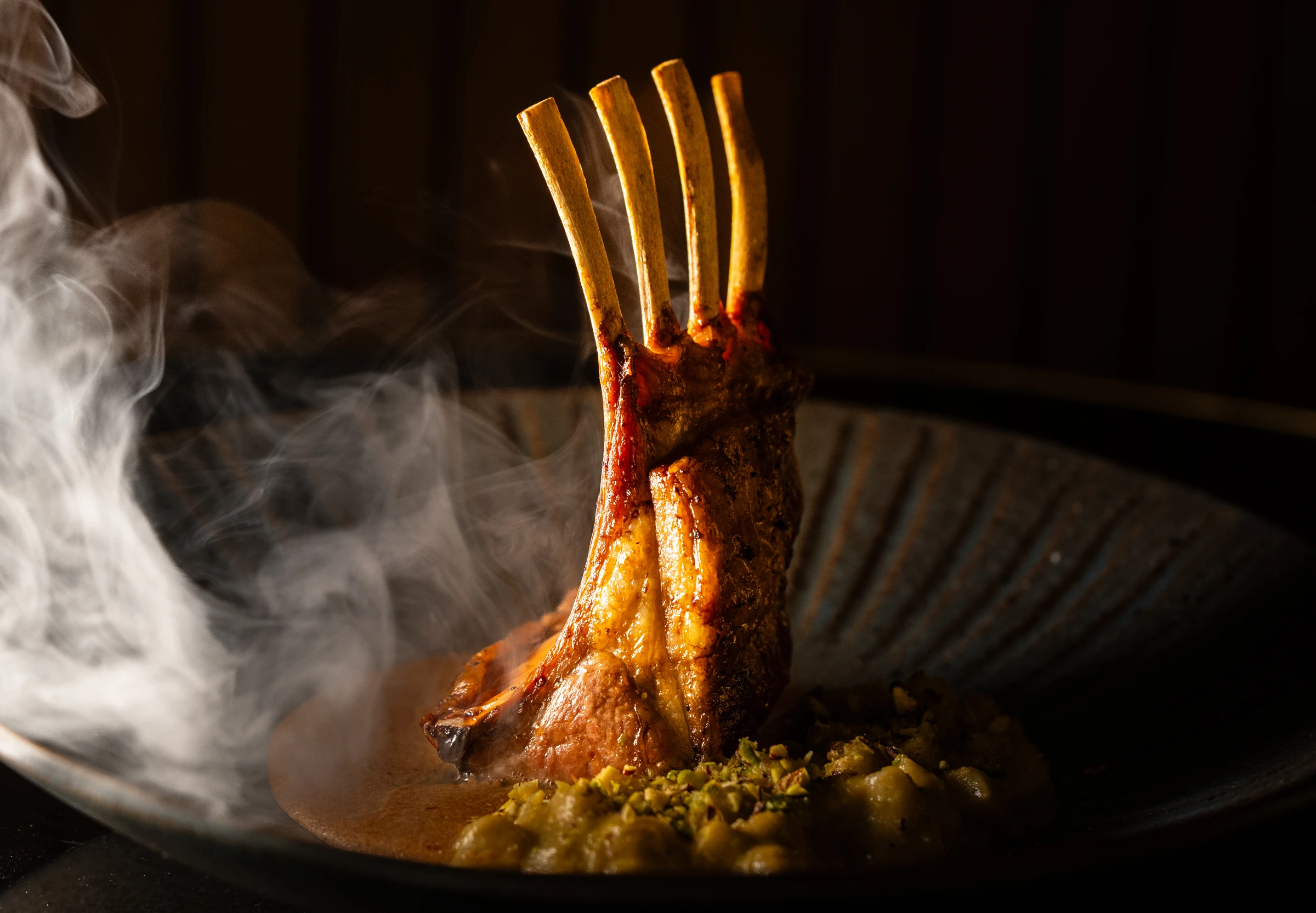 Fotografía gastronómica de un costillar servido entre humo en el restaurante Malaspina